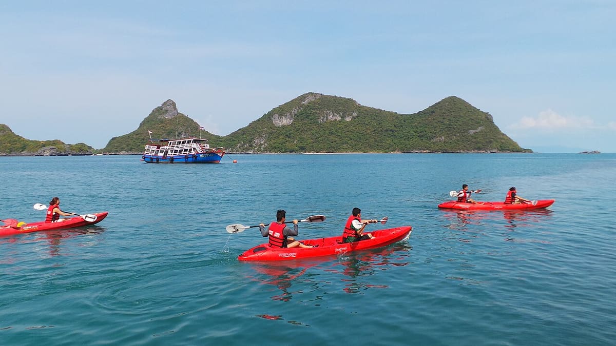 Kayaks on the water in front of limestone cliffs